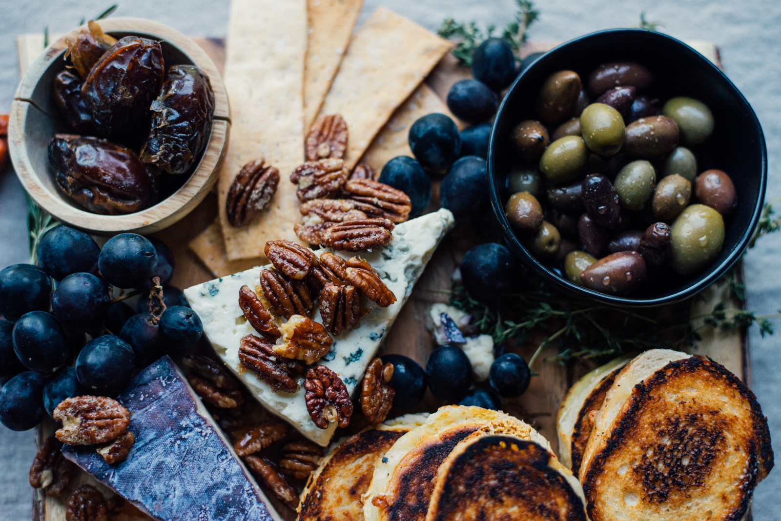 kid-friendly fall cheese board with dates, black grapes. maple glazed pecans, olives, and mini grilled cheese sandwiches