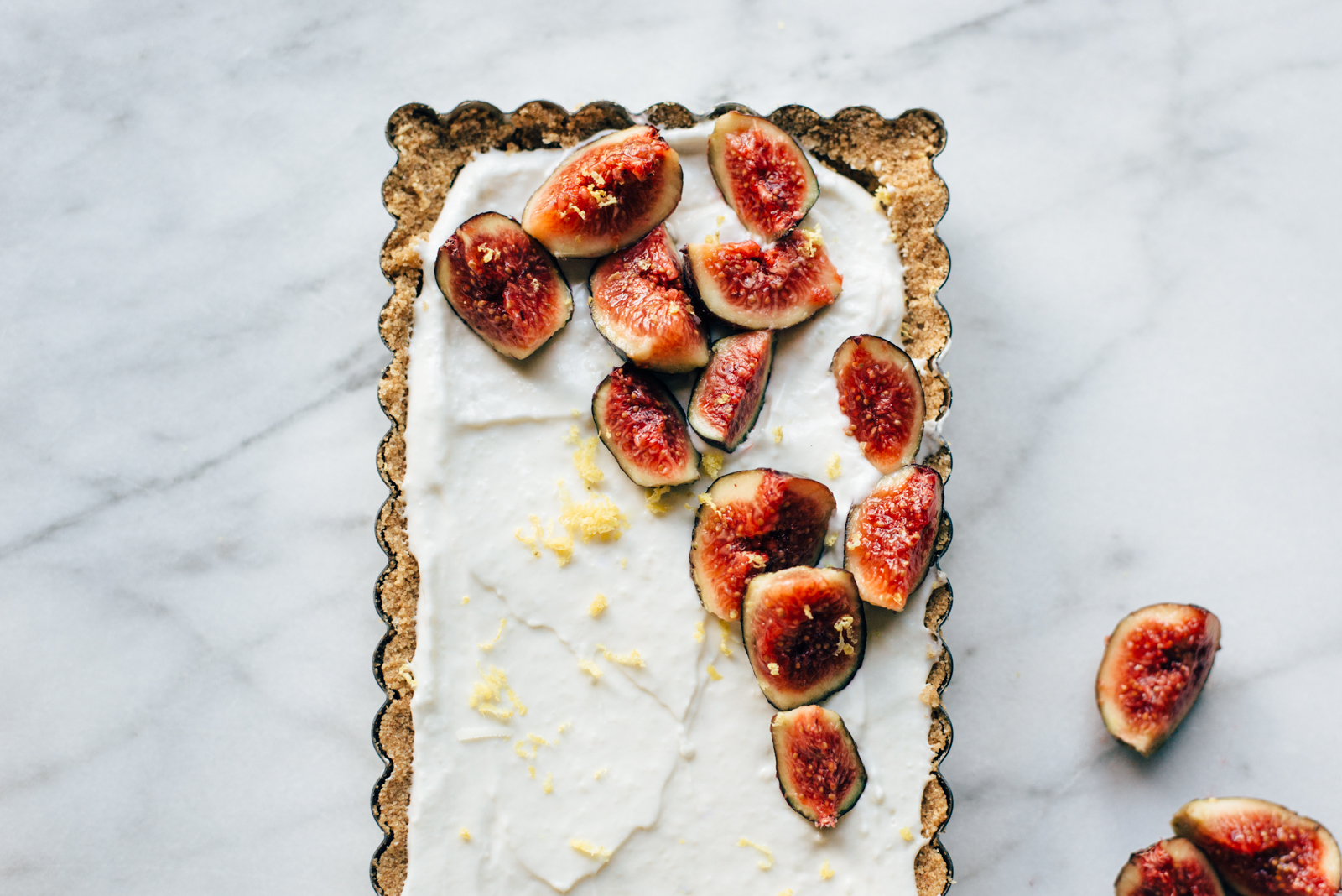 fresh figs on lemon cream tart with graham cracker crust on marble background