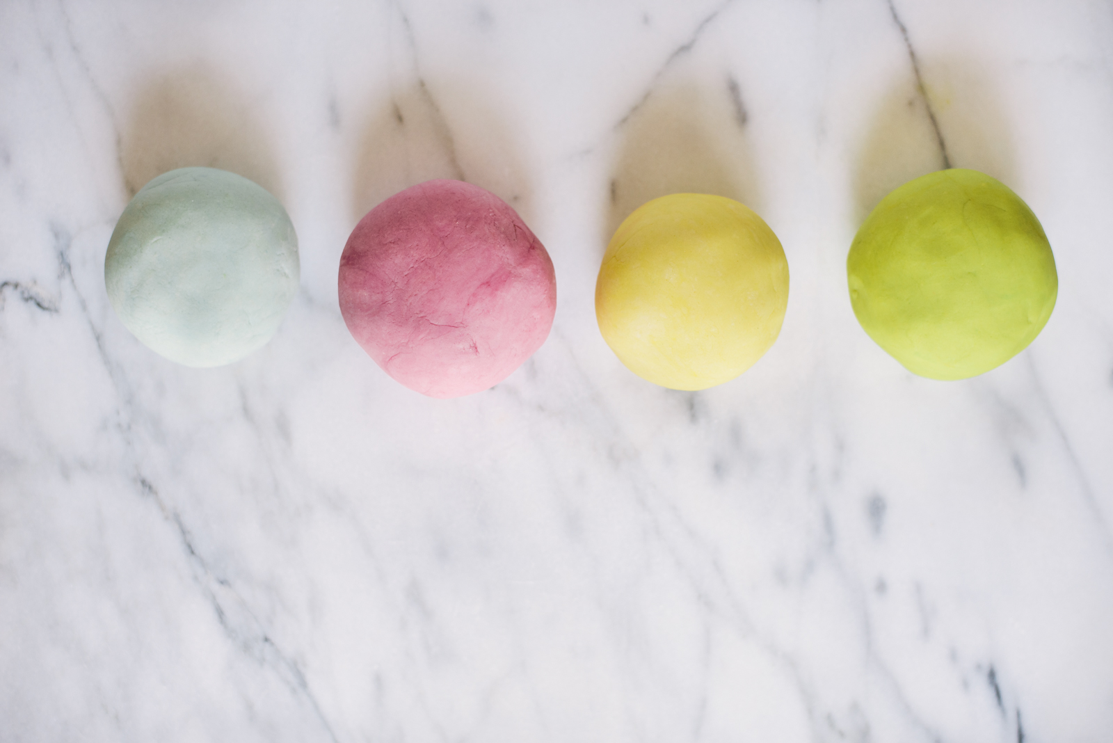 four essential oil play dough balls in natural colors on marble