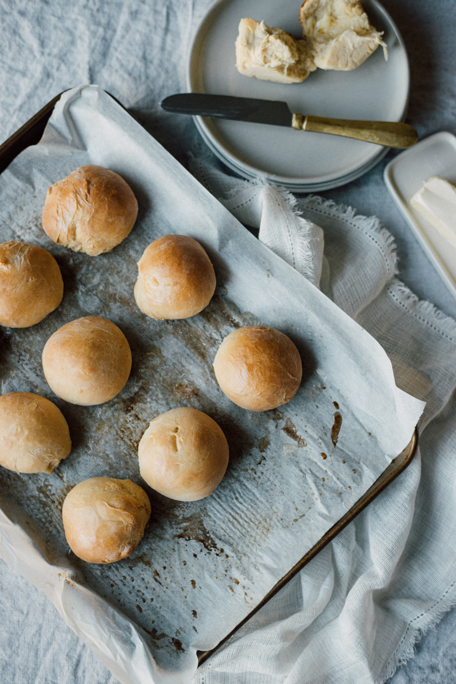 buttery thanksgiving parker house rolls on linen tablecloth with butter and white plates