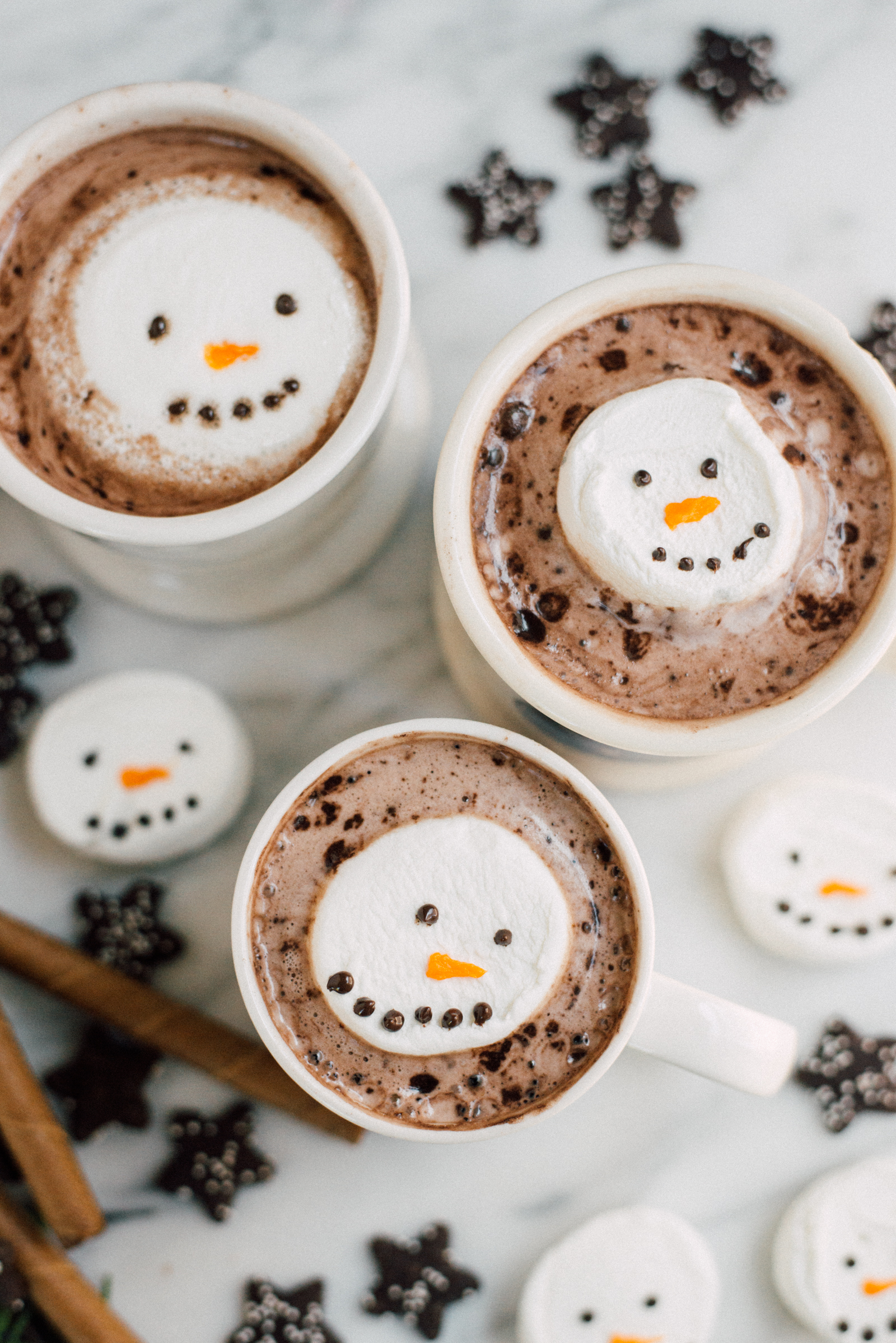 hot chocolate marshmallow snowmen in white mugs on marble
