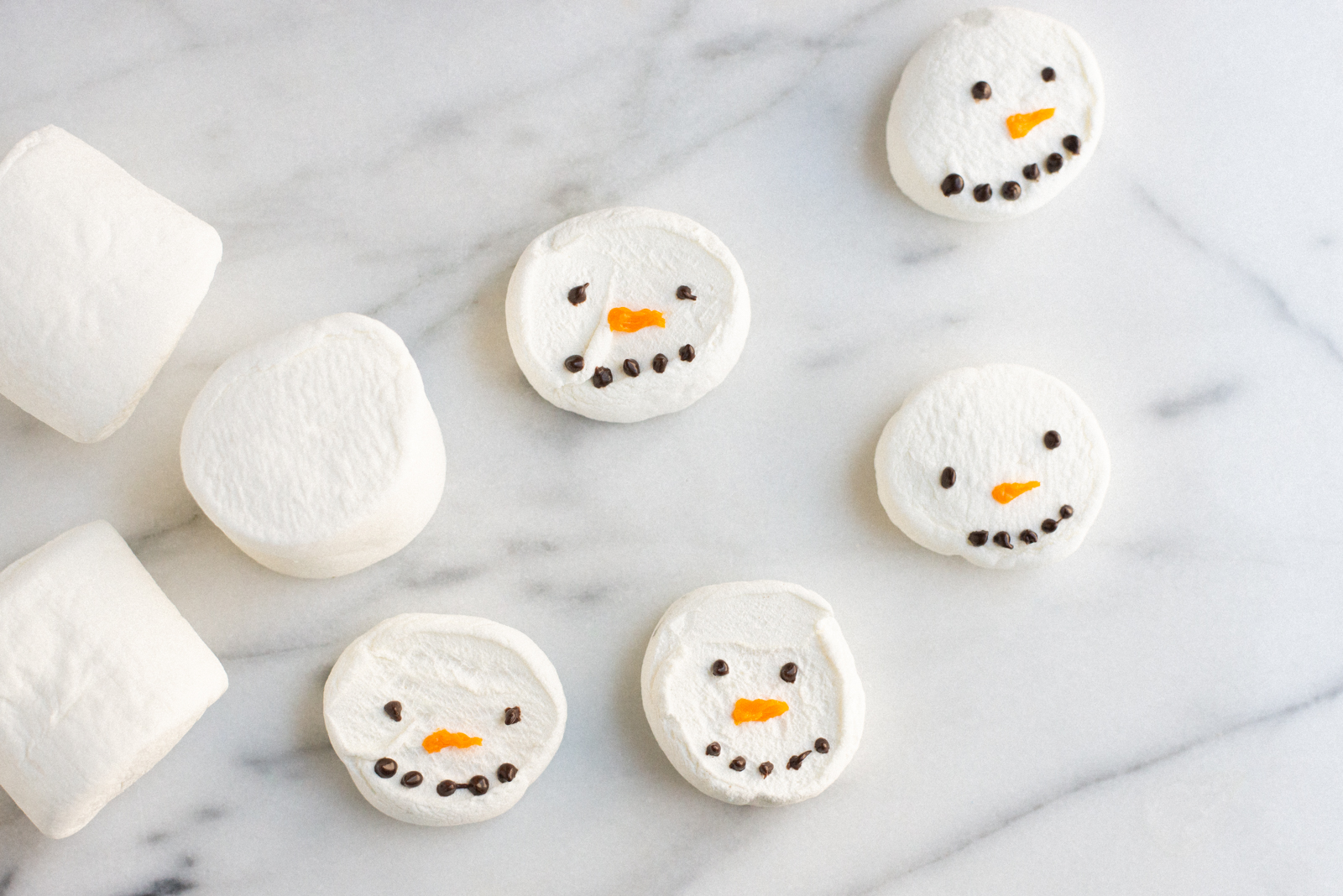 painting snowmen faces on marshmallows with candy melts