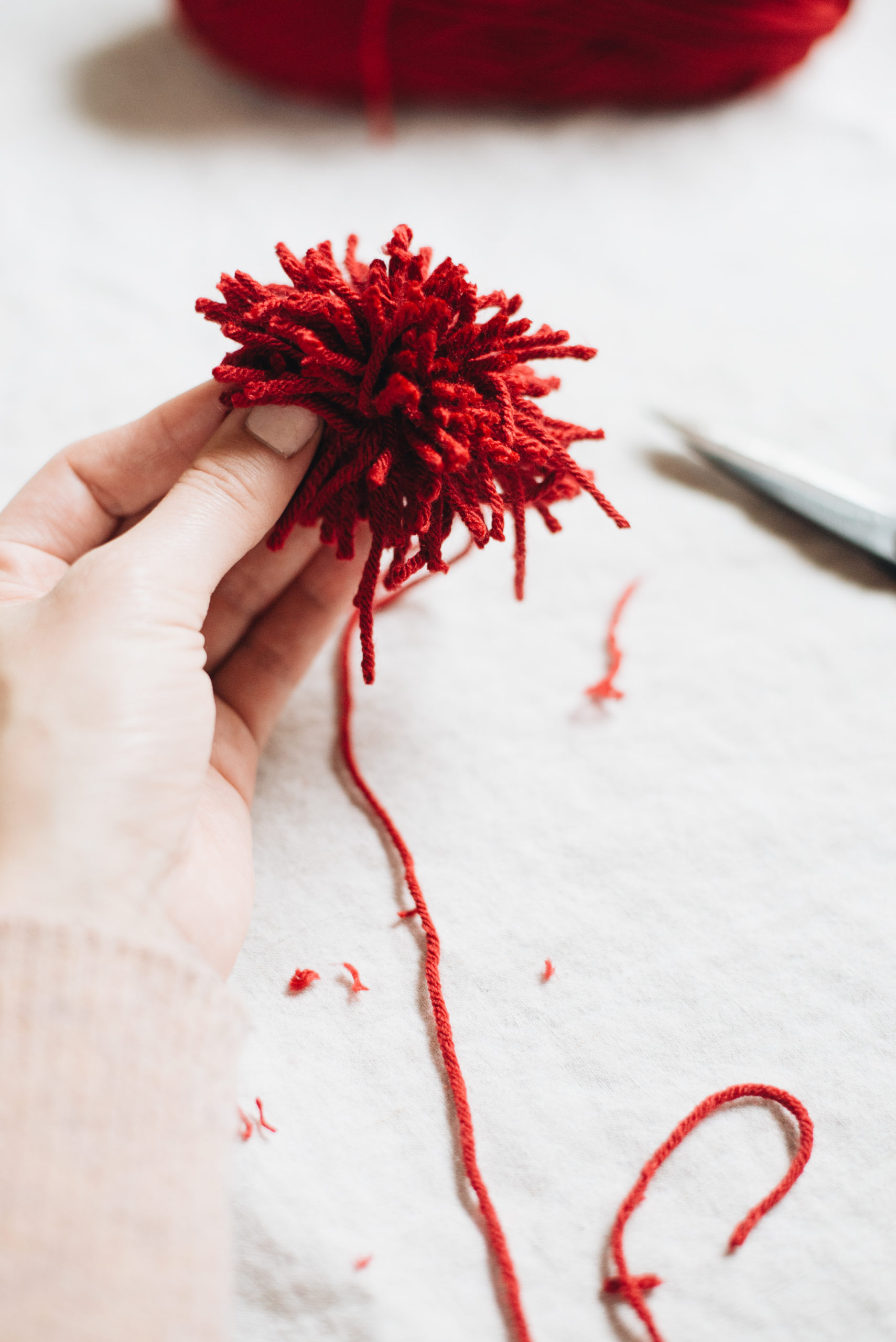 trim the loops of red yarn to make heart pom pom bookmarks